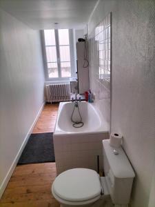 a white bathroom with a toilet and a sink at La maison des remparts in Falaise