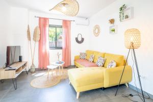 sala de estar con sofá amarillo y TV en Ô Ruisseau Lodge lodge Cocotier, en Saint-Louis