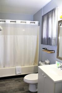 a bathroom with a white shower curtain and a toilet at Campbell's Motel Scottsburg in Scottsburg