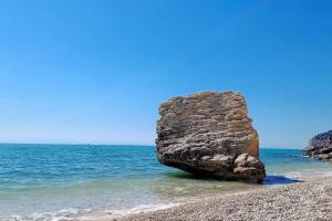 a large rock in the water on a beach at Casetta nel centro storico in Mattinata