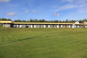 a large building with a flag in front of a field at Oasis Motel in Antigonish
