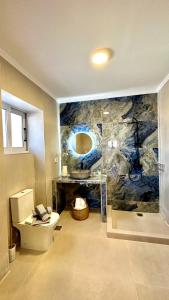 a bathroom with a toilet and a stone wall at Saint Nicolas luxury apartment in Methoni