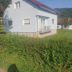 a white house with a balcony and a grass field at HOLIDAY HOUSE MARIC 