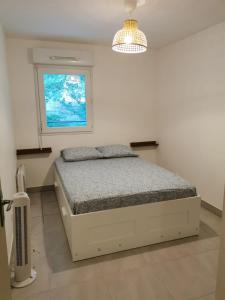 een witte slaapkamer met een bed en een raam bij Magnifique appartement pour 8 personnes à Montpellier - WIFI/PARKING in Montpellier
