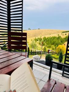 a book on a wooden table with a view of a field at Wild nest Deer Lux in Zlatibor