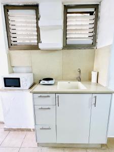 a kitchen with white cabinets and a sink and two windows at ТИХАЯ КВАРТИРА ДЛЯ ОТДЫХА! in Haifa