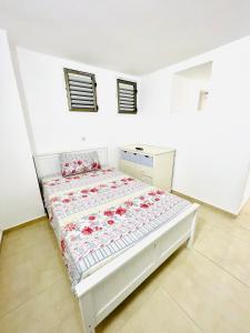 a white bedroom with a bed with flowers on it at ТИХАЯ КВАРТИРА ДЛЯ ОТДЫХА! in Haifa