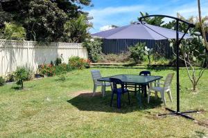 克羅納拉的住宿－Kurranulla Sapphire - Unit 1，院子里的桌子和椅子以及雨伞