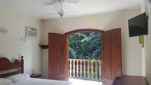 Pousada Dois Irmãos في ترينيداد: غرفة نوم بسرير وباب زجاجي منزلق