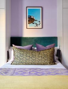a bed with a green headboard and some pillows at Pineapple House Boutique Hotel in Cape Town