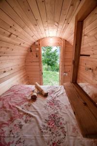 een groot bed in een houten kamer met een raam bij Cozy Barrel in the Hills in Nikšić