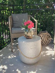 a vase of flowers on a table next to a chair at Apartmani Mate in Rogoznica