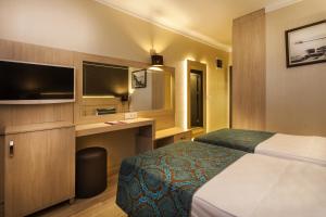 Una habitación de hotel con una cama, un escritorio y un televisor. en Parador Beach Hotel All Inclusive, en Alanya