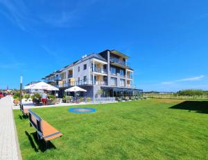 a large building with a green lawn in front of it at Apartament z basenem Sarbinowo in Sarbinowo