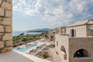 an external view of a stone building with a swimming pool at Dream Villas Stoupa in Stoupa