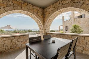 a dining room with a table and two arched windows at Dream Villas Stoupa in Stoupa