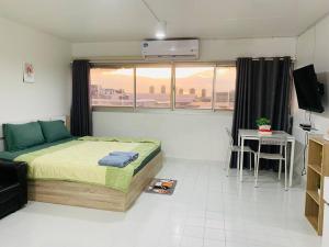 a bedroom with a bed and a table and a window at Condo popular T8 fl.12 in Thung Si Kan