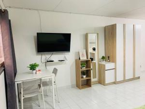 sala de estar con mesa y TV en la pared en Condo popular T8 fl.12 en Thung Si Kan