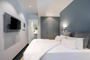 Schlafzimmer mit einem weißen Bett und einem Flachbild-TV in der Unterkunft Batschari Palais Baden-Baden in Baden-Baden