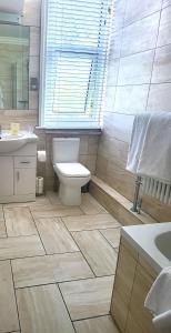 a bathroom with a toilet and a sink and a window at Sutherland House in Deal