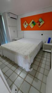 a white bed in a room with an orange wall at Ancorar Porto de Galinhas flat 7205 in Ipojuca