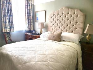 um quarto com uma grande cama branca e uma grande cabeceira de cama. em Sutherland House em Deal