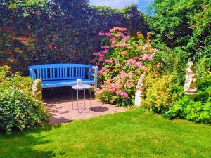 un banco azul sentado en un jardín con flores en Sutherland House, en Deal