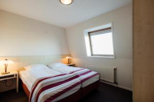 a small bedroom with a bed and a window at Appartementen Hotel Meyer in Bergen aan Zee