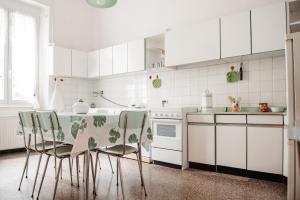 cocina con armarios blancos, mesa y sillas en Casa elegante in mezzo al verde, en La Spezia