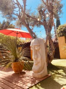 a statue of a head next to a plant and an umbrella at chez Guy in Marseille