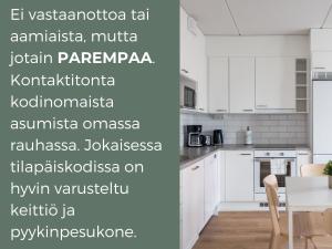 a white kitchen with white cabinets and a table at Hiisi Homes Espoo Finnoo in Espoo