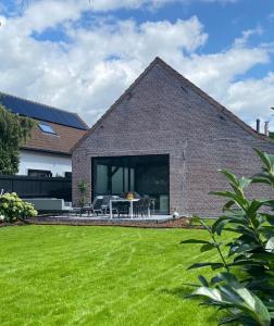 una casa de ladrillo con un césped verde delante de ella en Hoeve De Kleinheide, en Dessel