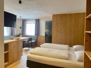 a hotel room with two beds and a desk at Ciasa La Rösa in Badia