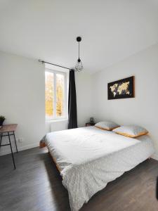 a white bedroom with a bed and a window at 2 Apparts, Riom, 8 pers in Riom