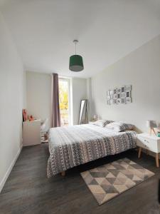 a white bedroom with a bed and a window at 2 Apparts, Riom, 8 pers in Riom