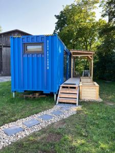 a blue outhouse with a porch and a deck at Tiny House im Seecontainer mit Parkplatz, Glasfaser, Netflix, Veranda und gehobener Ausstattung in Coburg