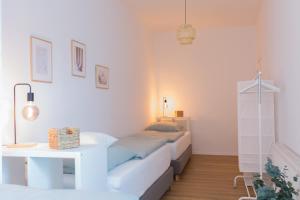 a white bedroom with a bed and a table at Modernes Apartment Lieblingsfleck I 2 Schlafzimmer I 4 Betten I Zentrumsnah in Eberswalde