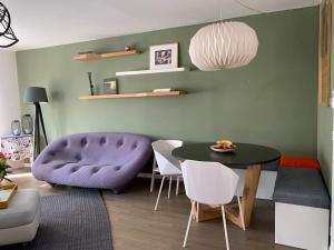 sala de estar con sofá púrpura, mesa y sillas en Appartement terrasses proche Orly & Paris, en Chevilly-Larue