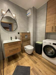a bathroom with a toilet sink and a washing machine at Komfortowy Apartament Nadbrzeżna blisko Warszawy z Parkingiem in Ożarów Mazowiecki