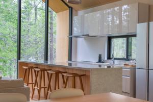 a kitchen with wooden stools and a counter with windows at Kouzan Woods in Kaributo