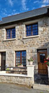 ein Steinhaus mit einer Bank davor in der Unterkunft Gite des Forges in Moncontour