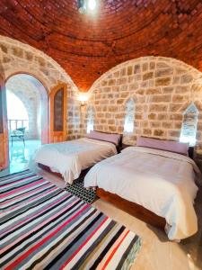 a bedroom with two beds and a stone wall at كمبوند قرية تونس in Tunis