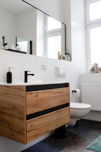 a bathroom with a sink and a toilet and a mirror at Modernes Apartment Lieblingsfleck I 2 Schlafzimmer I 4 Betten I Zentrumsnah in Eberswalde