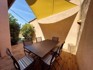 a table and chairs with a yellow umbrella on a wooden deck at Maison de César in Saint-Saturnin-dʼApt