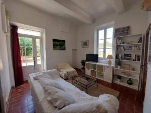 uma sala de estar com um sofá branco e uma televisão em Maison de César em Saint-Saturnin-dʼApt