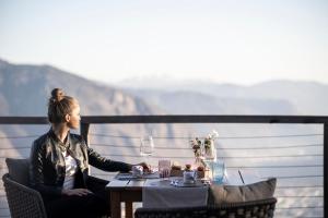 Eine Frau, die mit einem Glas Wein am Tisch sitzt. in der Unterkunft Hotel Belvedere - Fine Dining, Hideaway & SPA in Jenesien