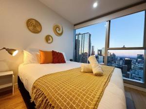 een slaapkamer met een bed en uitzicht op de stad bij City SkyRise View 2BR Southern Cross in Melbourne