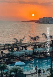a sunset over a swimming pool at a beach at Sarande Barracuda View Apartment in Sarandë