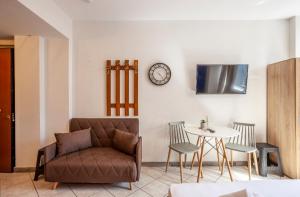 a living room with a couch and a table and a clock at Railway Area Studio parking in Thessaloniki