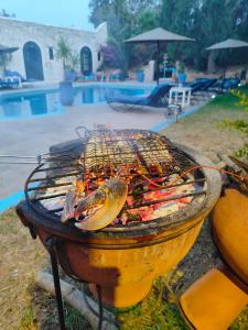 a grill with meat and seafood on it next to a pool at Riad Eucalyptus by Caravanserail in Essaouira